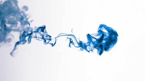 Isolated Blue Ink Cloud floating in clear water. Macro Shot on White Background with selective focus framed for vertical video