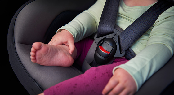 A mother fastening the buckle on a child’s car seat