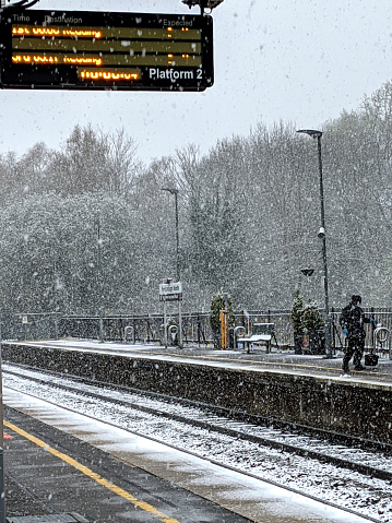 Waiting for a train at the train station in the snow, the train is running late