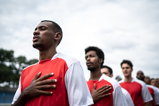 Soccer players listening to anthem on field