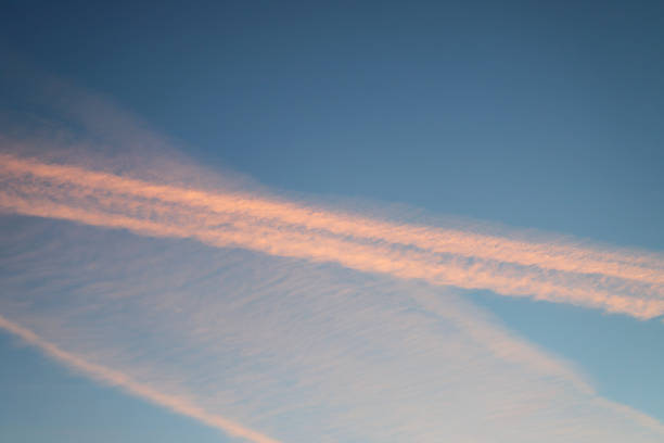 Blue summer sky with clouds and pink vapor trail as a background