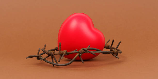 istock On the brown surface is a red heart, which is surrounded by barbed wire. 1398376495