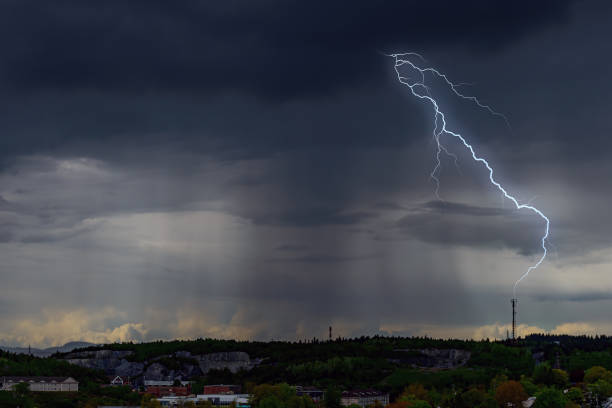 Lightning Strike On A Dark Day Lightning strikes a communications tower in the distance. Very dark clouds with heavy rain from above, neighborhood below is also dark. Room for text. lightning tower stock pictures, royalty-free photos & images