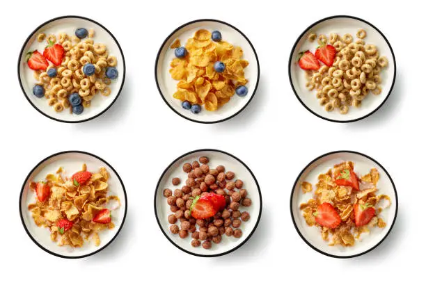 bowls of breakfast cereal with milk and berries isolated on white background, top view