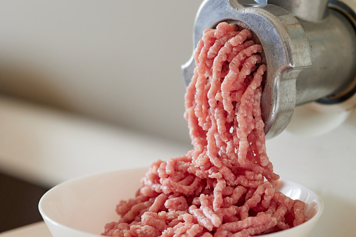 mince meat with an electric meat grinder in the domestic kitchen, selective focus