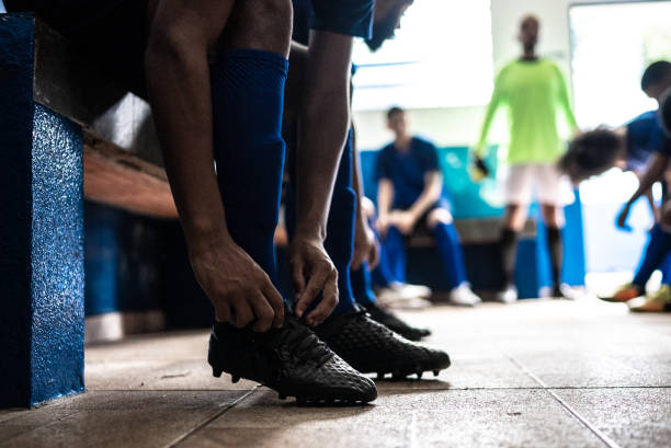 Soccer player tying shoelaces while preparing for match in the locker room Soccer player tying shoelaces while preparing for match in the locker room football socks stock pictures, royalty-free photos & images
