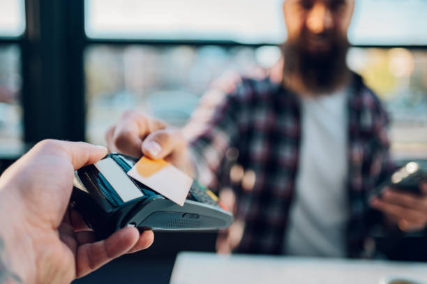 istock Man making transaction while using credit card and a payment terminal in a cafe 1398379423
