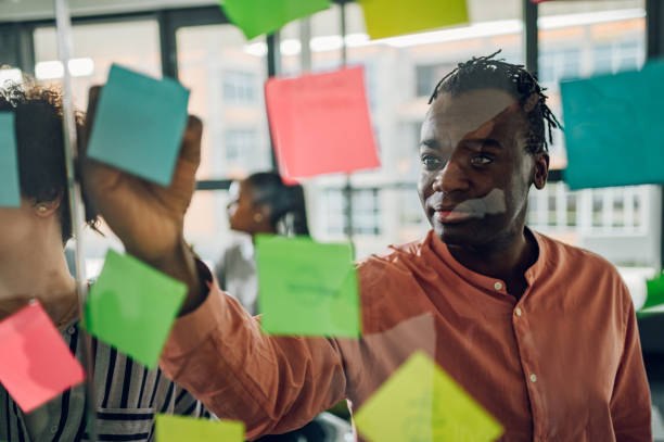istock Multiracial team at work writing ideas on sticky notes on the glass wall 1398379460