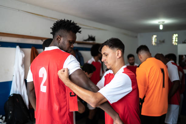 istock Soccer player helping the team captain getting ready before a match in the locker room 1398379523