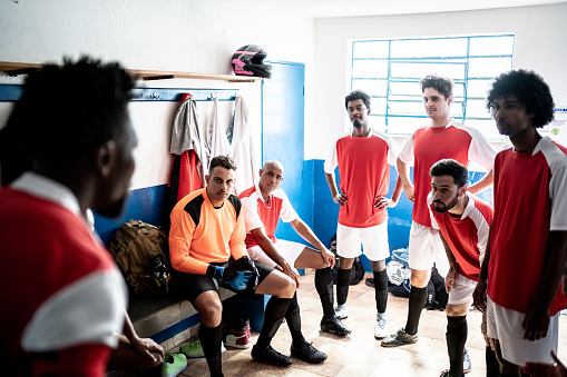 Soccer players listening to team captain before a match in the locker room