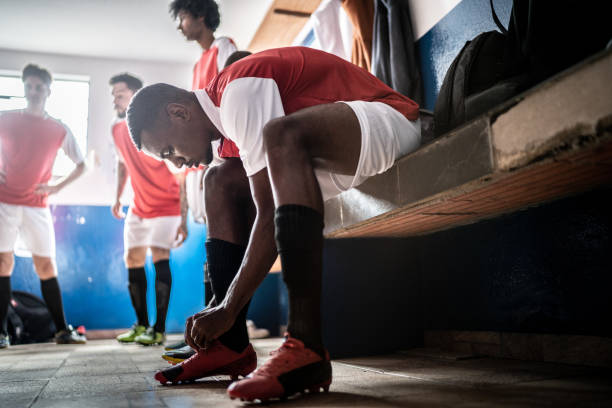 istock Soccer player tying shoelace before a match in the locker room 1398379625