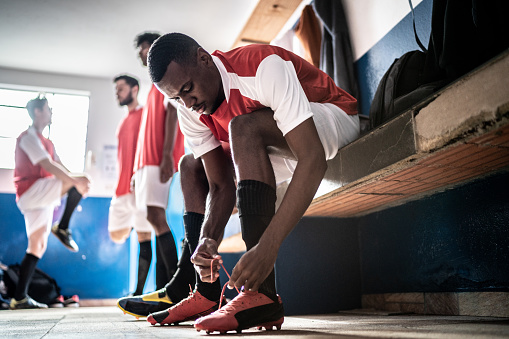 Soccer player tying shoelace before a match in the locker room