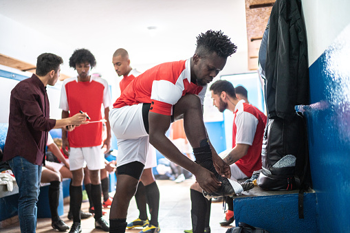 Soccer player tying shoelace in the locker room