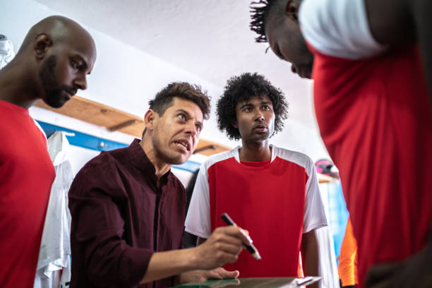 Soccer coach talking about strategies with soccer players in the locker room Soccer coach talking about strategies with soccer players in the locker room club soccer photos stock pictures, royalty-free photos & images