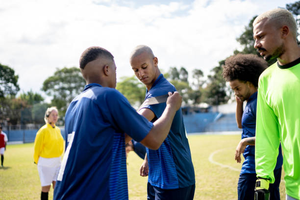 istock Soccer player helping team captain putting on arm band 1398381035