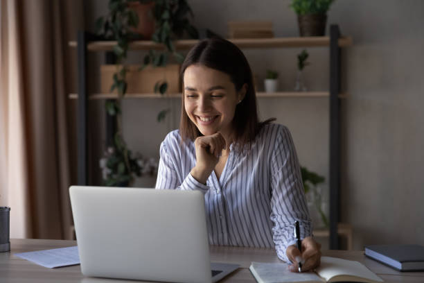 istock Happy pretty student girl watching online training, writing notes 1398385333