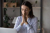 Religious millennial business woman praying at workplace