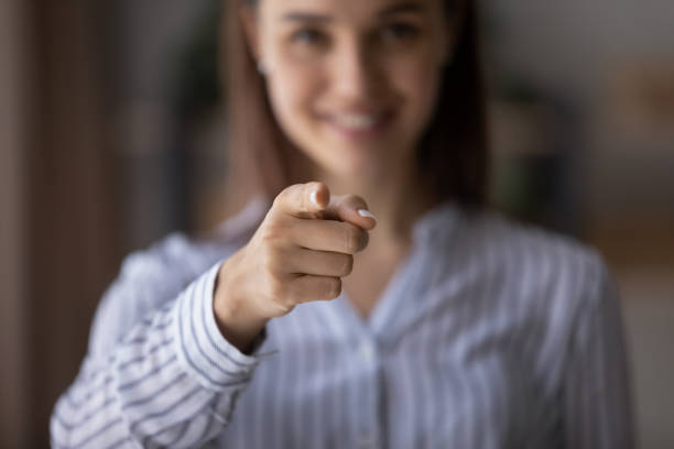 Happy blurred young woman pointing index finger at camera