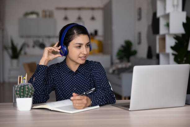 focused smiling indian student girl in headphones studying from home - indian ethnicity audio imagens e fotografias de stock