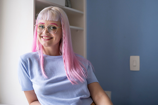 Portrait of a young woman with pink hair and eyeglasses