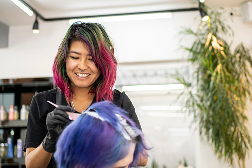 Hairdresser dyeing client's hair at hair salon