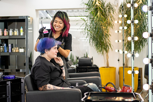 Hairdresser dyeing client's hair at hair salon