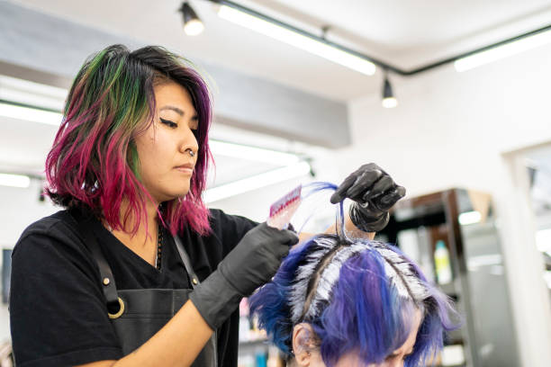 парикмахер окрашивает волосы клиента в парикмахерской - blue tint стоковые фото и изображения