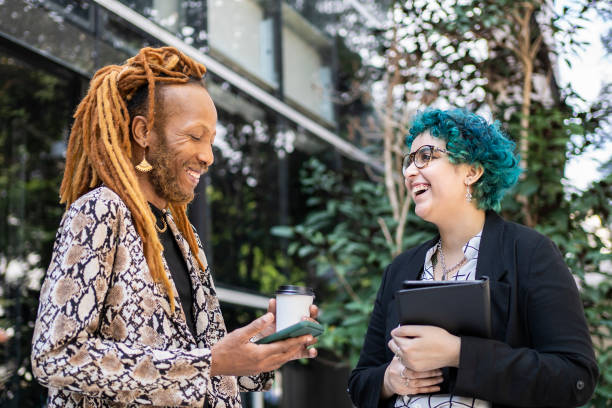 Black man with dreadlock hair and his coworker talking outside the office building stock photo