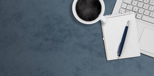 istock top down view of laptop computer, coffee cup and notepad with pen on dark desk 1398394754