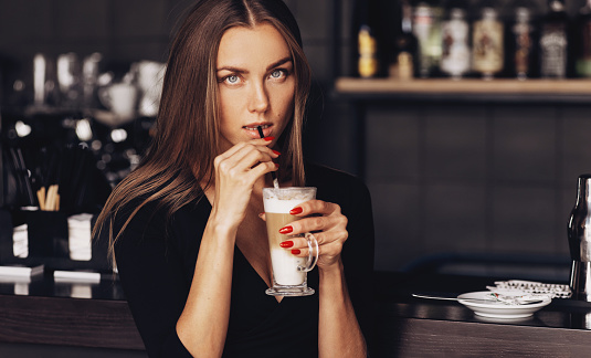 Portrait of woman drinking coffee latte in loft cafe