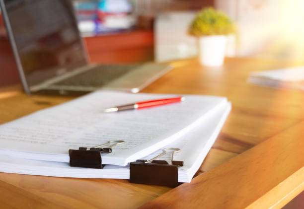 paperworks with black paperclips on top on wooden table in office with office supplies