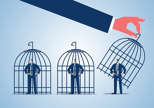 Hand holding a cage to lock a businessman standing in a row into a cage or release a businessman in the cage