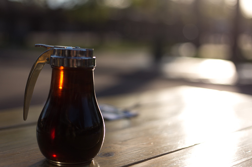 Pitcher of Syrup on Picnic Table Outside, Morning Sunlight