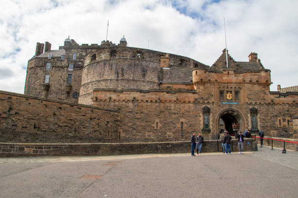 Majestic Edinburgh Castle perches on rugged rock, stone walls rising above lush greenery. A timeless Scottish fortress bathed in sunlight, conveying history, strength, and culture—perfect for editorial travel, heritage, and tourism themes.