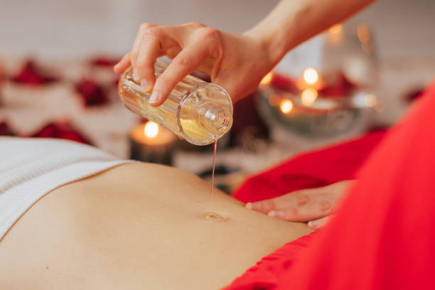 femme maître du reiki verse de l’huile pour le massage sur le corps féminin, concept de santé mentale - warmly photos et images de collection