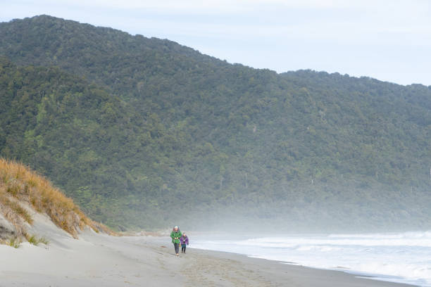 Young man runs along a pathway on a cliff above the sea