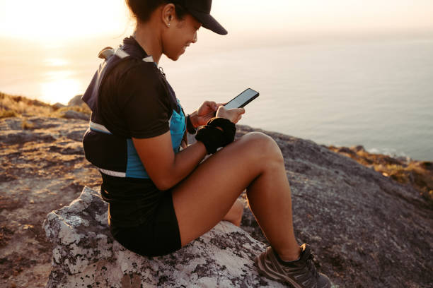 istock Trail runner holding smartphone while sitting on peak at sunset 1398422814