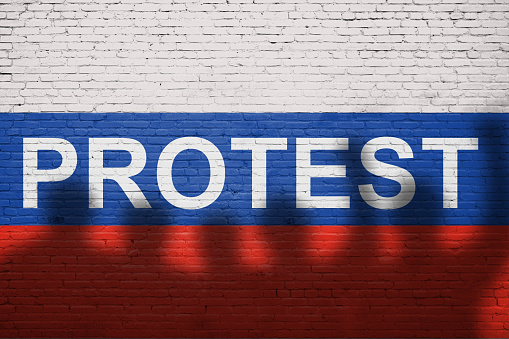 Flag of Russia painted on a brick wall with word PROTEST