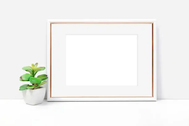 Horizontal white and gold frame on a light background with a flower. Frame mockup for your design.