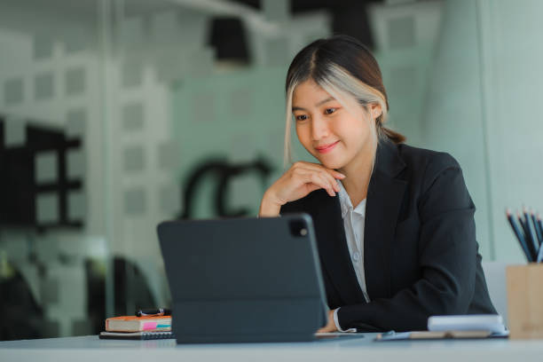 une femme d’affaires asiatique est heureuse de travailler dans un bureau moderne à l’aide d’une tablette. portrait d’un agent marketing travaillant à distance dans un bureau. - massage ball photos et images de collection