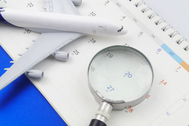 istock Magnifying glass and airplane model on calendar. 1398432115