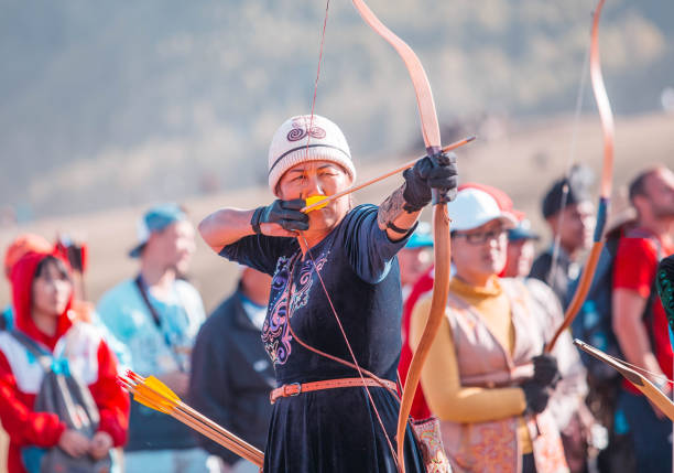 Isyk-Kul, Kyrgyzstan - September ‎29, ‎2018: Woman in Kyrgyz national dress with an arrow in a bow focused on hitting a target during World Nomad Games
