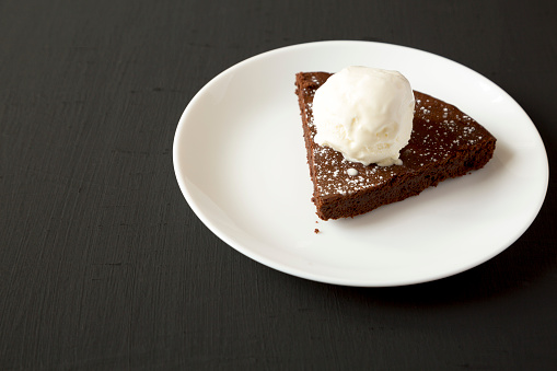 Homemade Chocolate Cake with Ice Cream on a black surface, side view. Copy space.