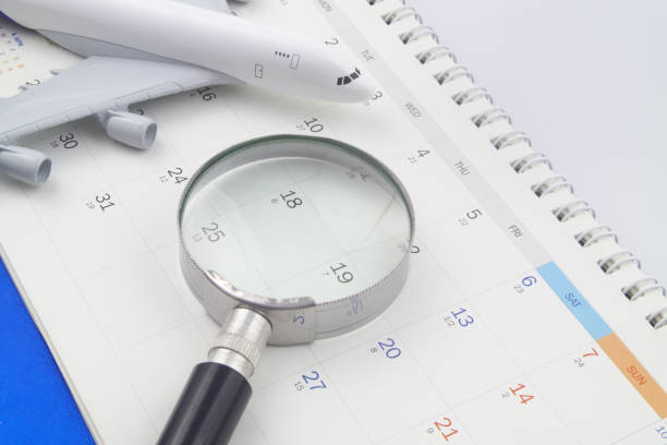 istock Magnifying glass and airplane model on calendar. 1398436510