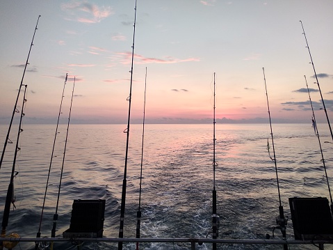Multiple fishing rods over the sea with beautiful pink sunset sky - Sea fishing - Indonesia