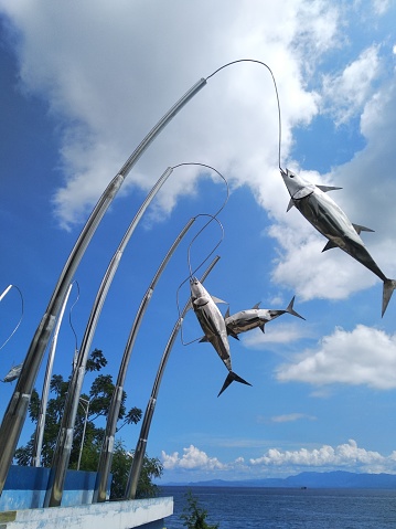 Metallic sculpture of fishing rods with fishes caught on the line over the sea - Indonesia - Ternate island