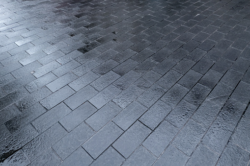 Square ground paved with wet floor tiles after rain