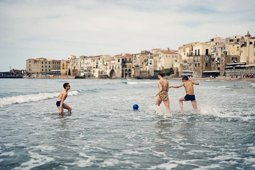Three teenage kids are playing with ball on beach. There are having a lot of fun throwing and catching the ball in the waves. Springtime, off-season vacations day in Cefalu, Sicily, Italy.
Shot with Canon R5