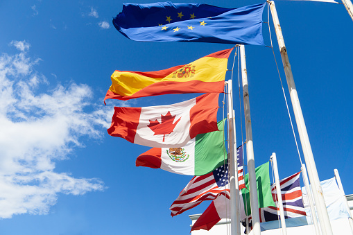 International cooperation: hands hold different national flags up towards the sky.