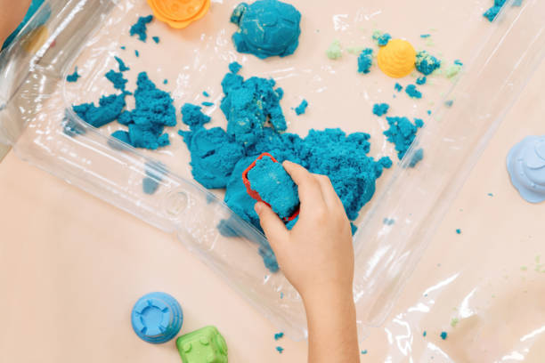 istock kinetic sand. children's hands play with multi-colored polymer sand. 1398454413